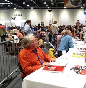 Chris Foss at the LonCon3 art show, signing copies of his newest art book for a long line of fans